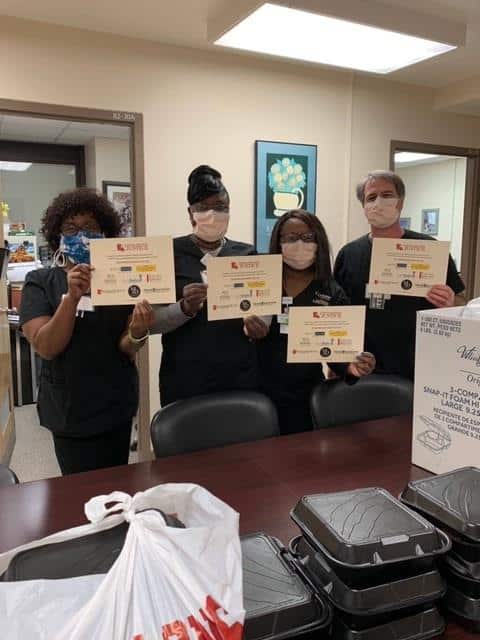 Staff of Morris & Dewett all wearing masks and holding certificates
