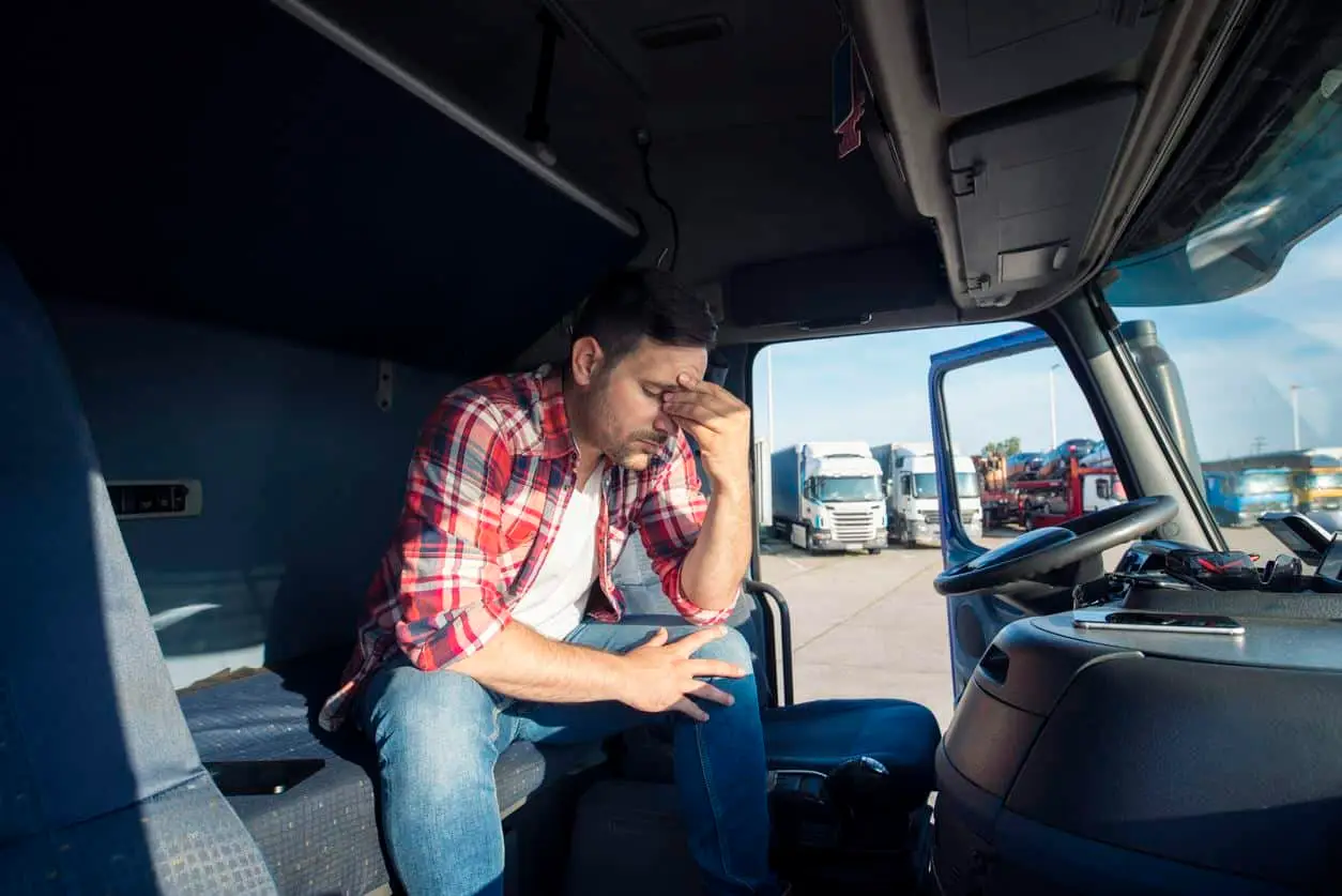 Stressed-truck-driver-rubbing-eyes-in-cab