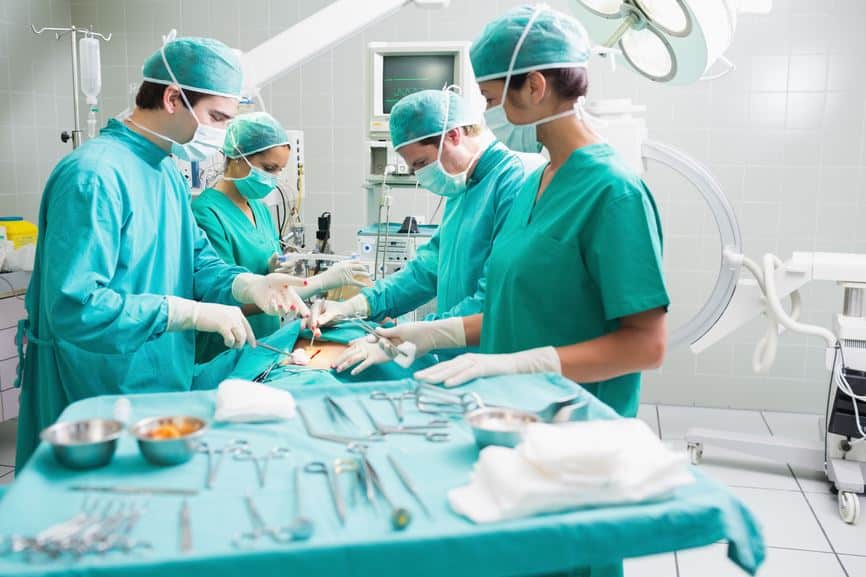 Side view of a surgical team operating a patient in an operation theatre