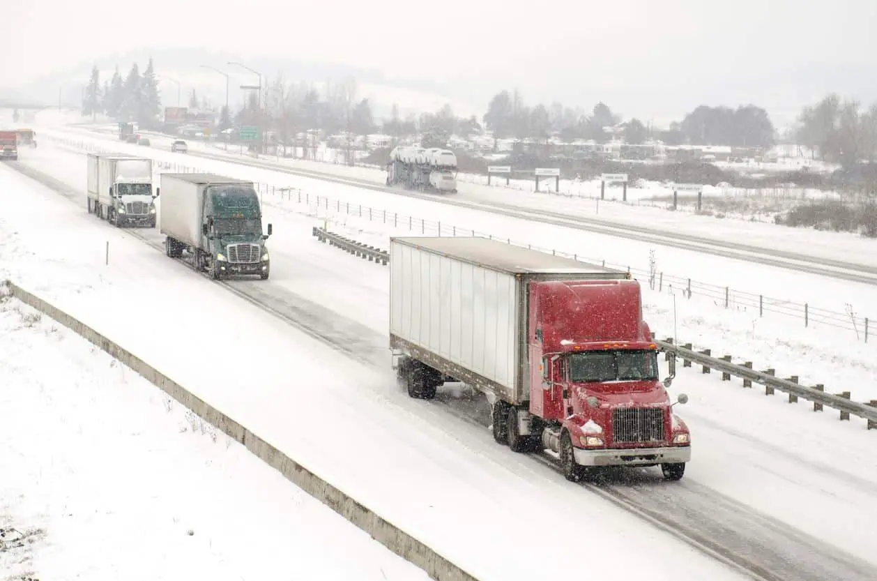 Semi truck traffic on Interstate 5 during a winter snow and freezing rain storm