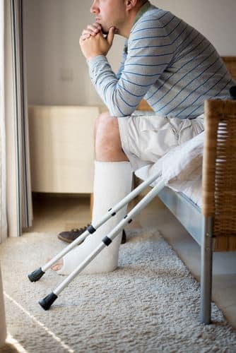 Injured man sitting with crutches car accident injuries can vary by severity and the area of the body that’s damaged. Generally, however, these injuries are either: