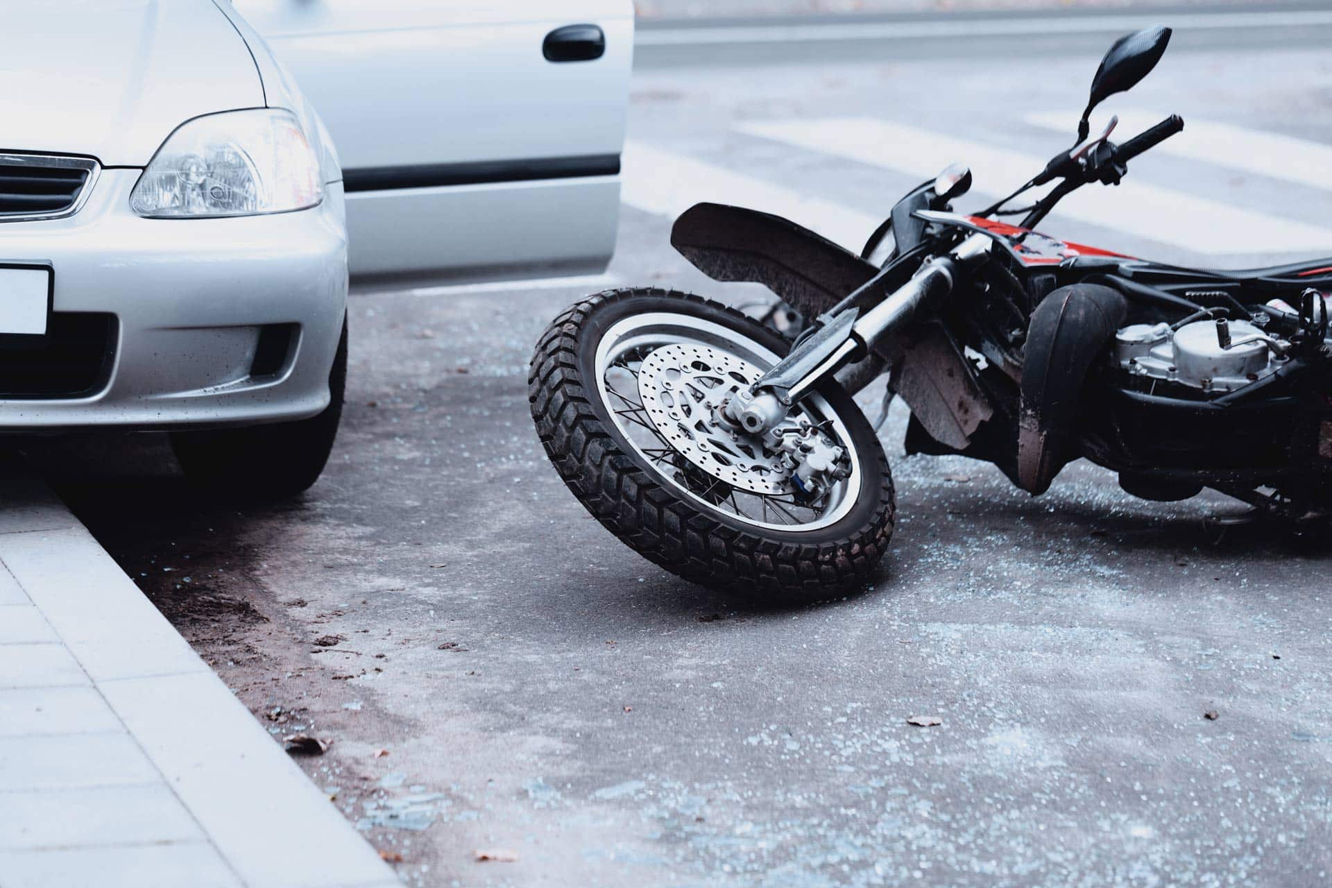 Motorcycle lying on the road and car standing with open door after a collision
