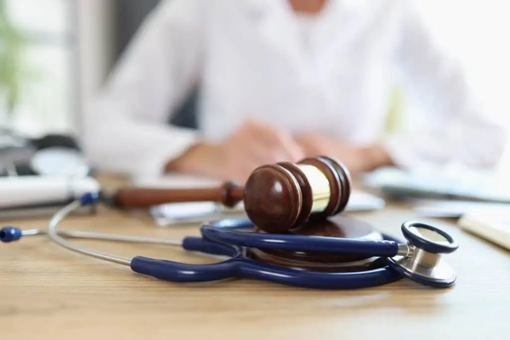 Closeup of judge gavel of stethoscope doctor in background writing notes