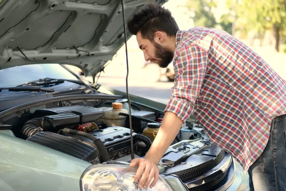 Young handsome man looking under car hood