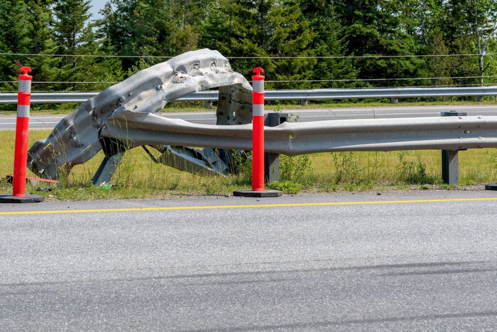A bent and twisted guard rail at the side of a highway.