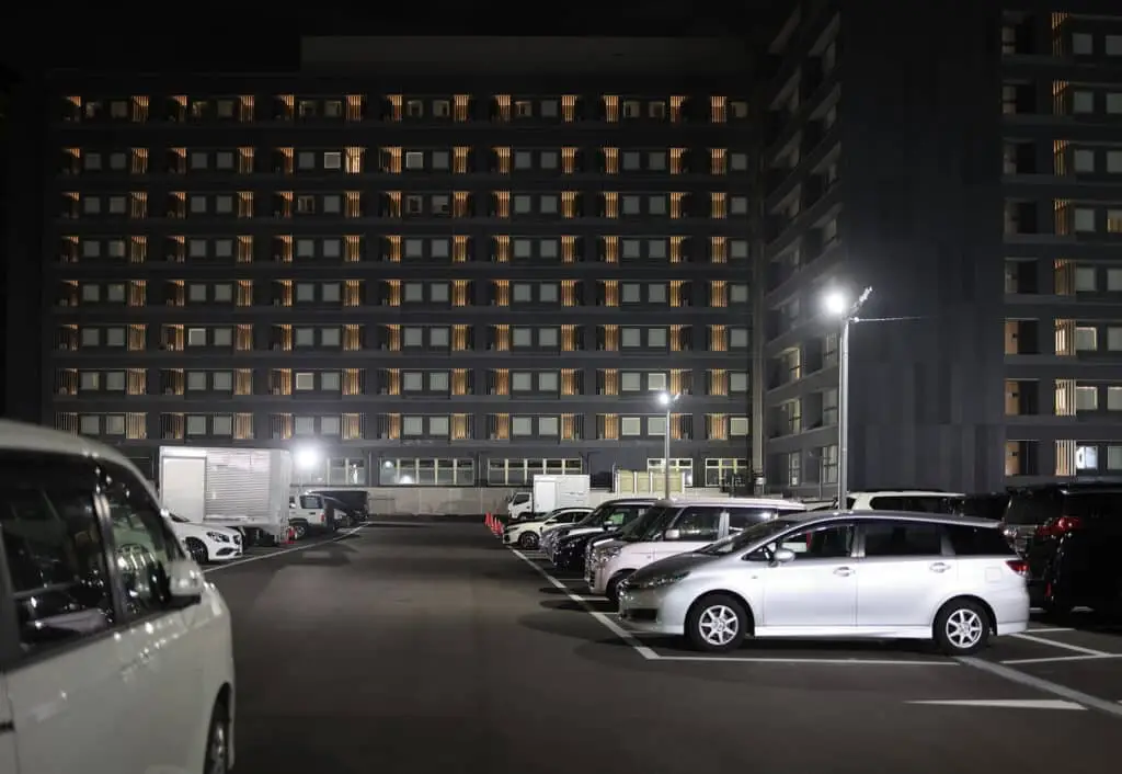 Full parking lot by multi-story hotel building at night