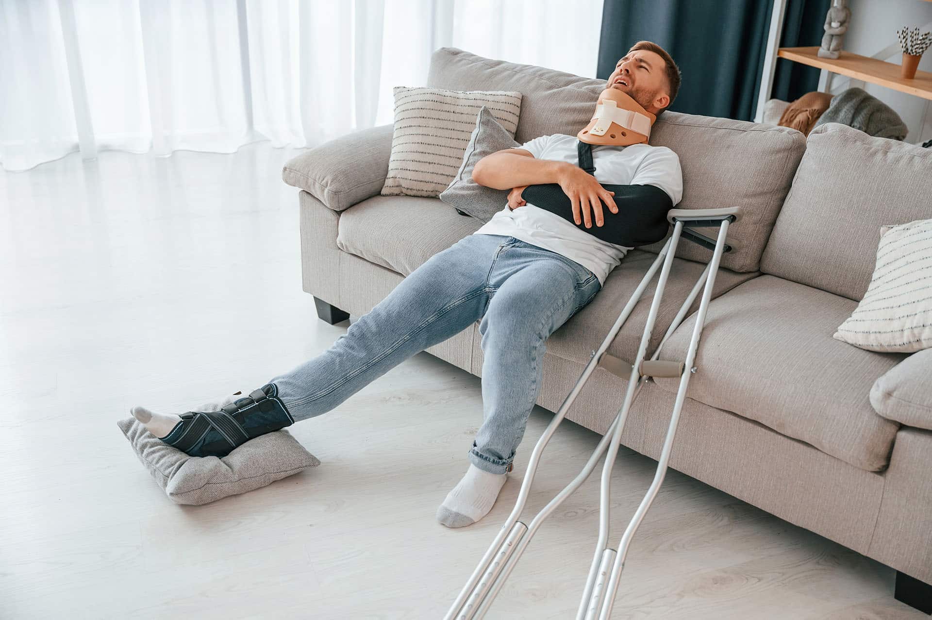 Man with crutches is at home indoors.
