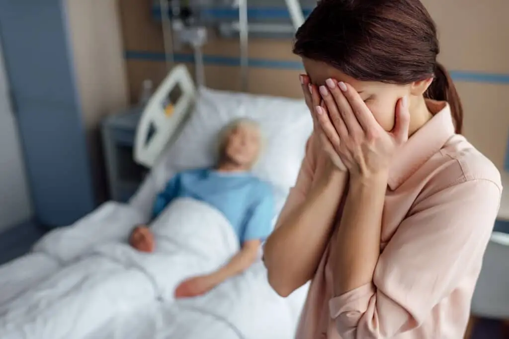 Crying daughter with sick mother in bed on background in hospital