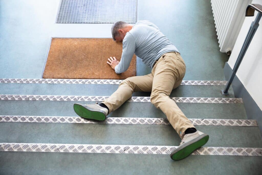 Mature man lying on staircase after slip and fall accident