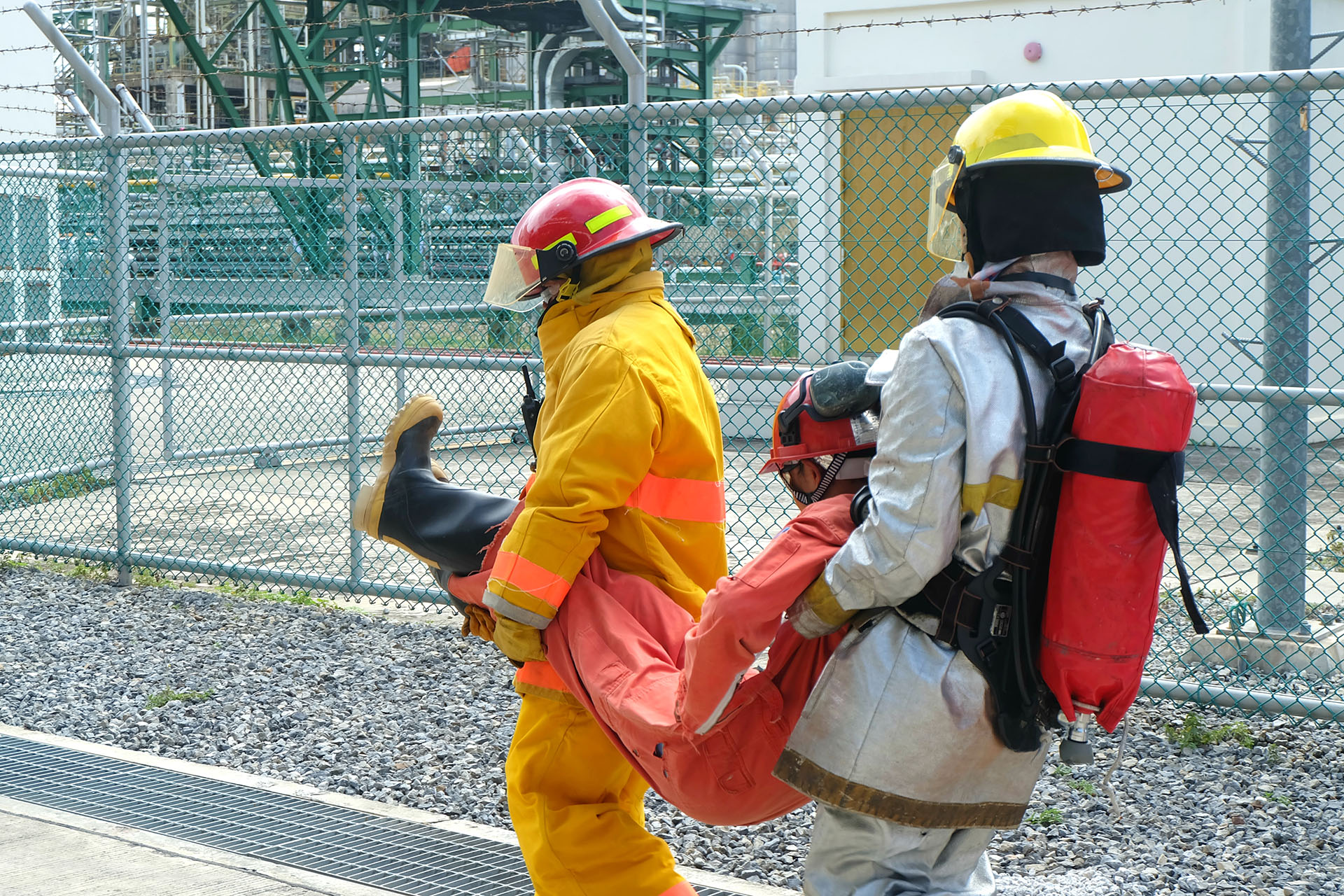 Two fireman are moving patients to a safe area and sending them to the field medical team as part of emergency drills or emergency drill training at a chemical plant oil and gas factory.