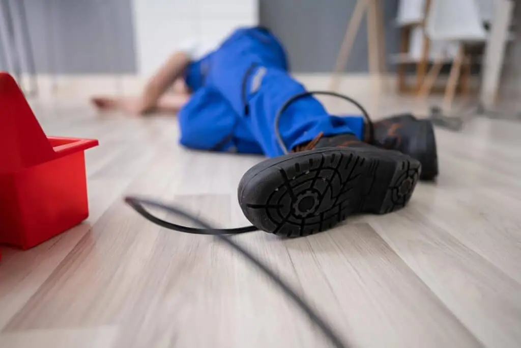 Low section of male electrician wrapped in wire fallen on floor