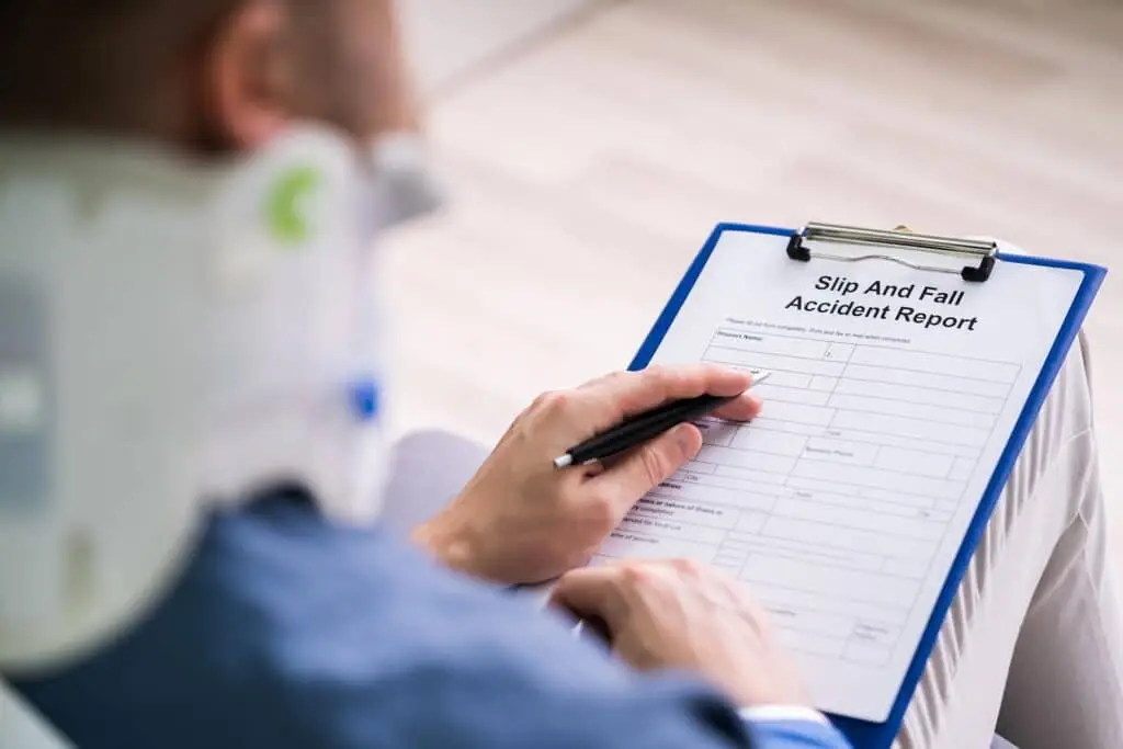 Close-up of a businessperson with broken arm filling health insurance claim form