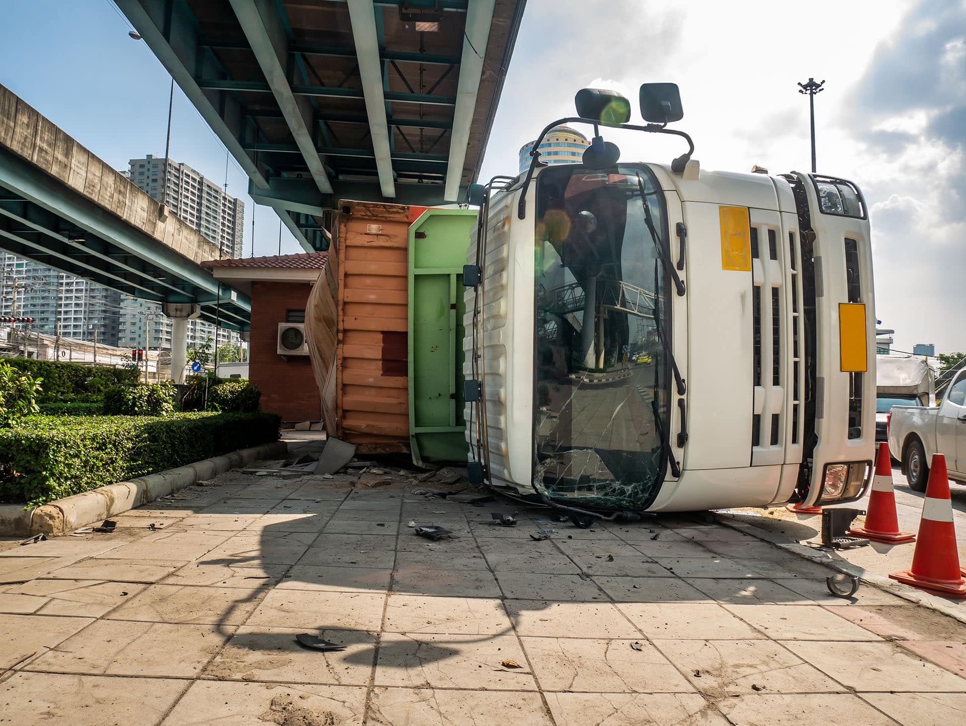 A truck carrying a container overturned on a road under a bridge over an intersection