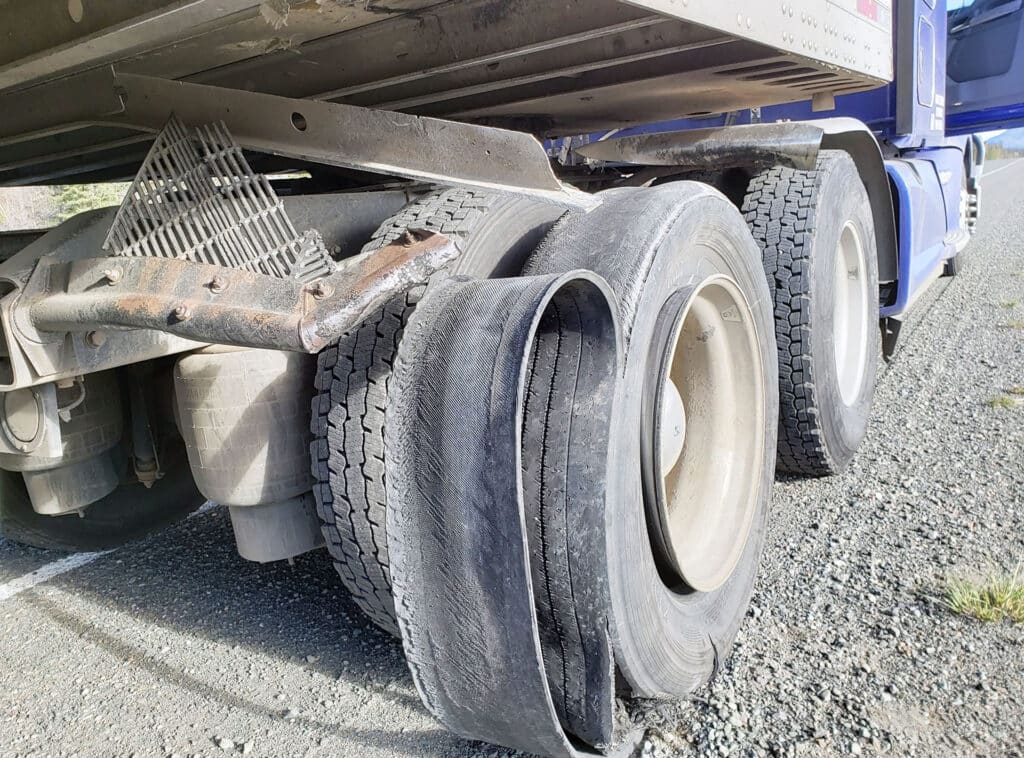 Damaged 18 wheeler semi truck burst tires on the shoulder