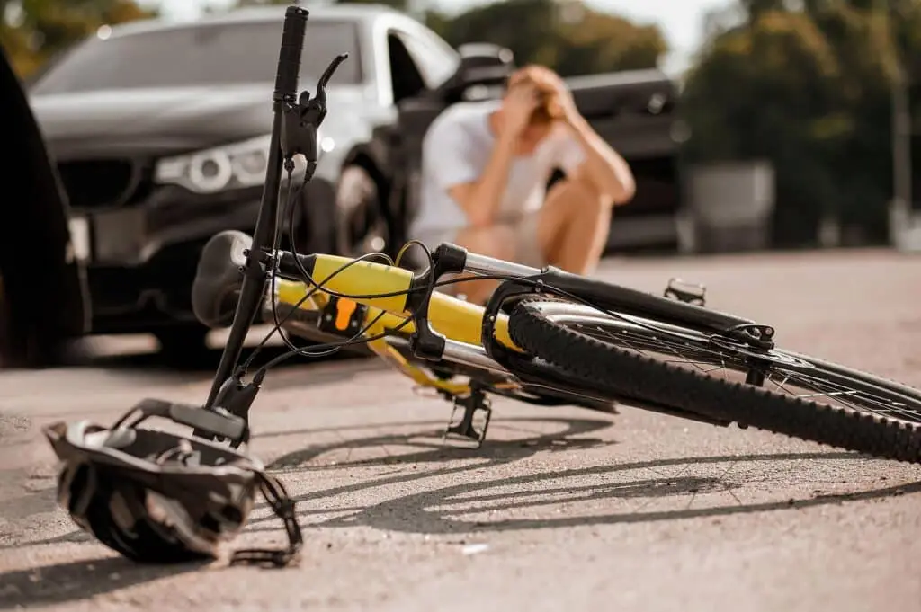 Bicycle and helmet on road and driver near car in a bicycle accident