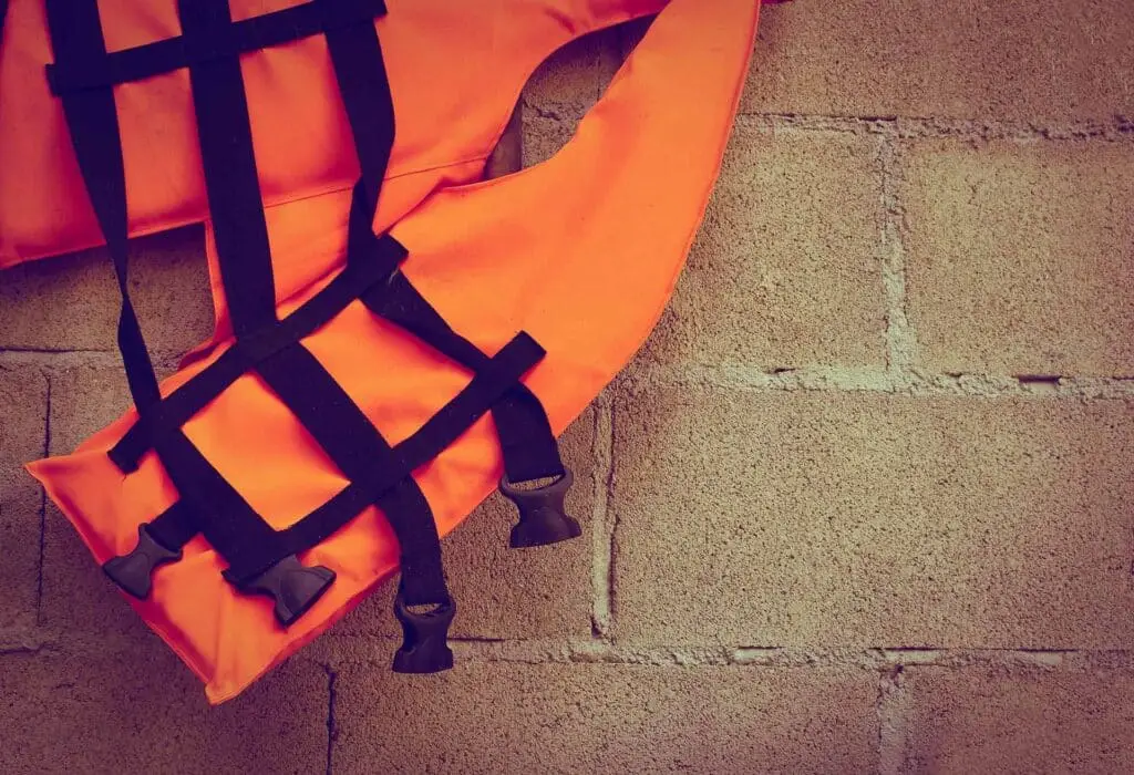 Part of orange life jacket lean on block wall