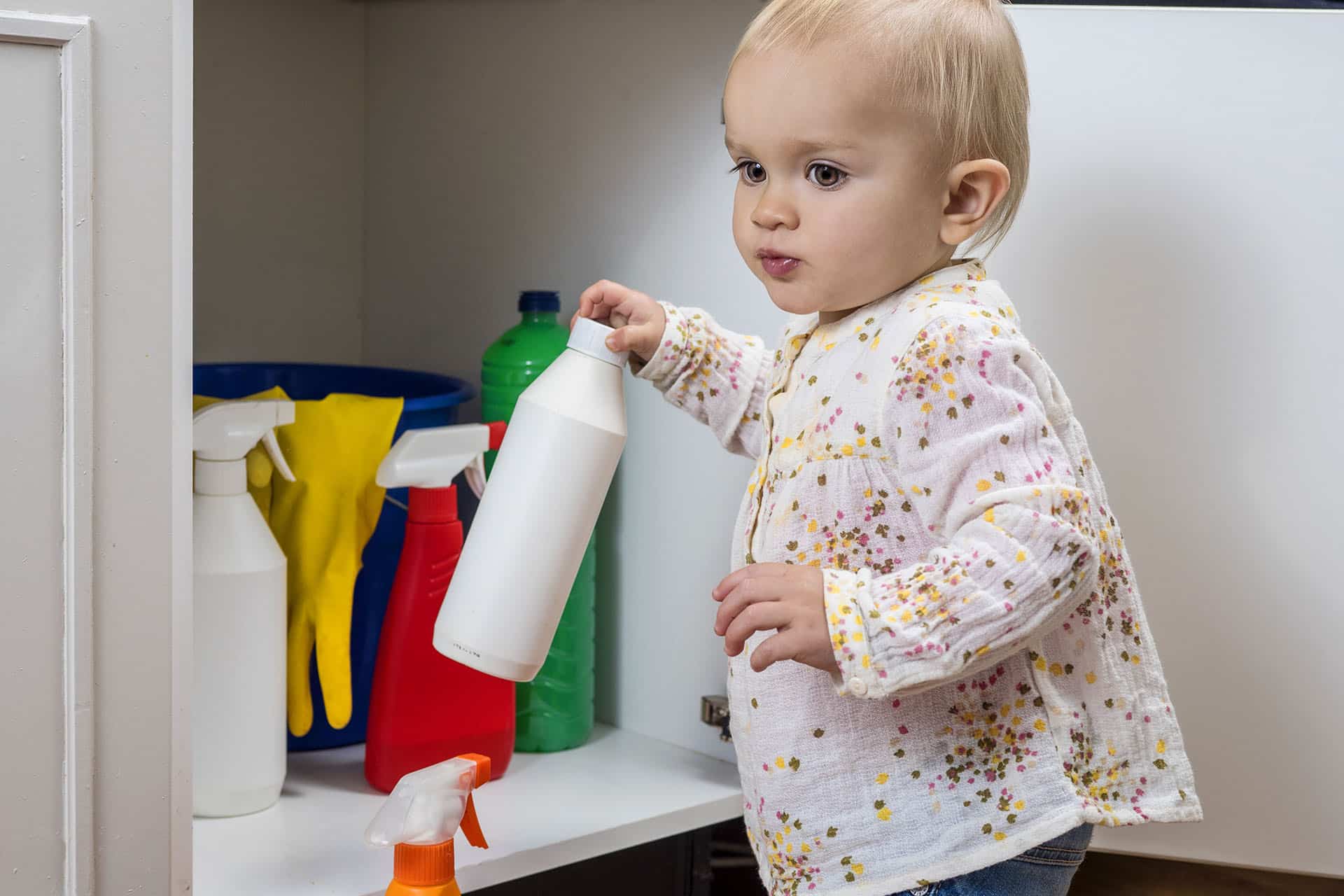 Toddler playing with household cleaners at home