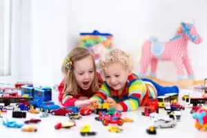 Little toddler boy and girl playing with model car collection on the floor.