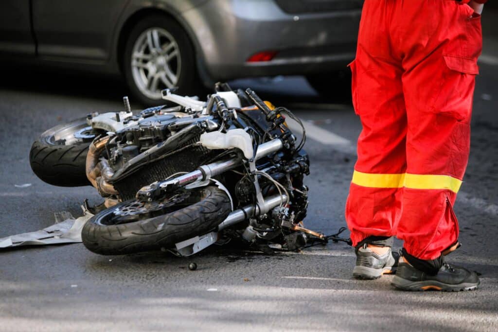 Crashed motorcycle after road accident with a car on a city street
