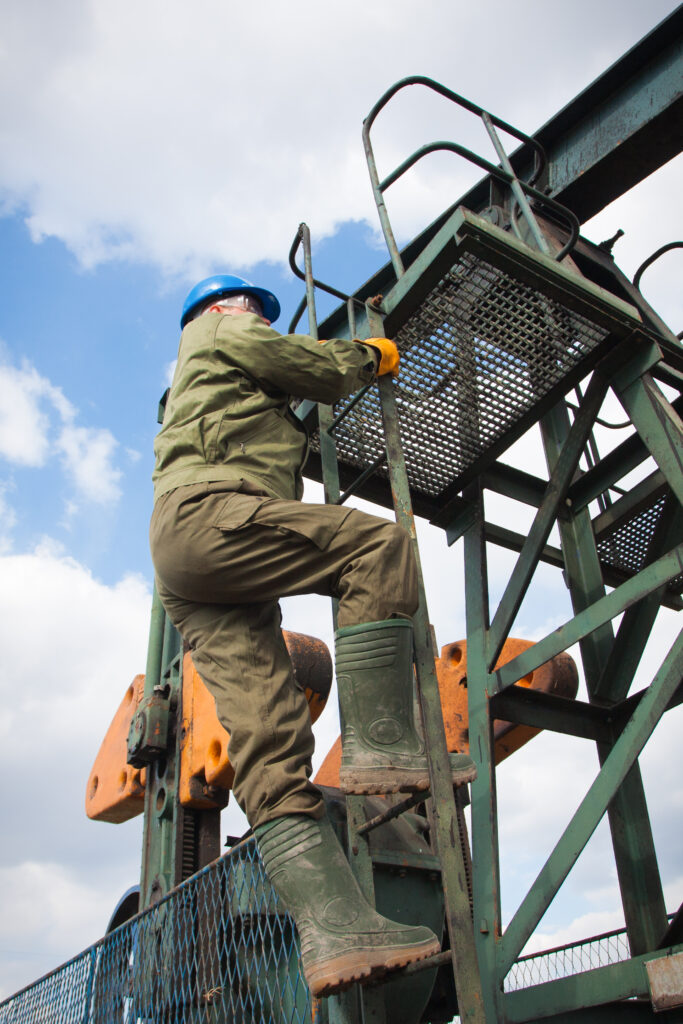 Oilfield worker climbing down from a platform on a drill site
