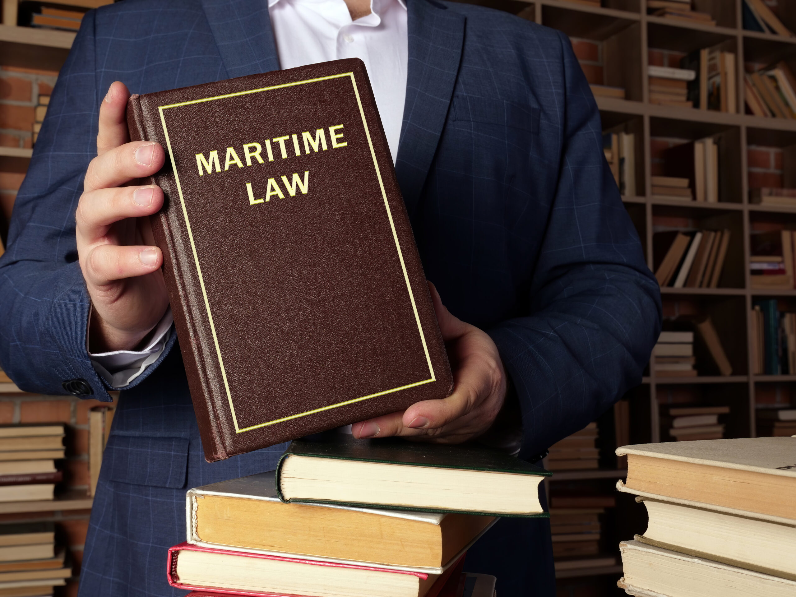 a law book being held may a man in a blue blazer with maritime law written on the cover