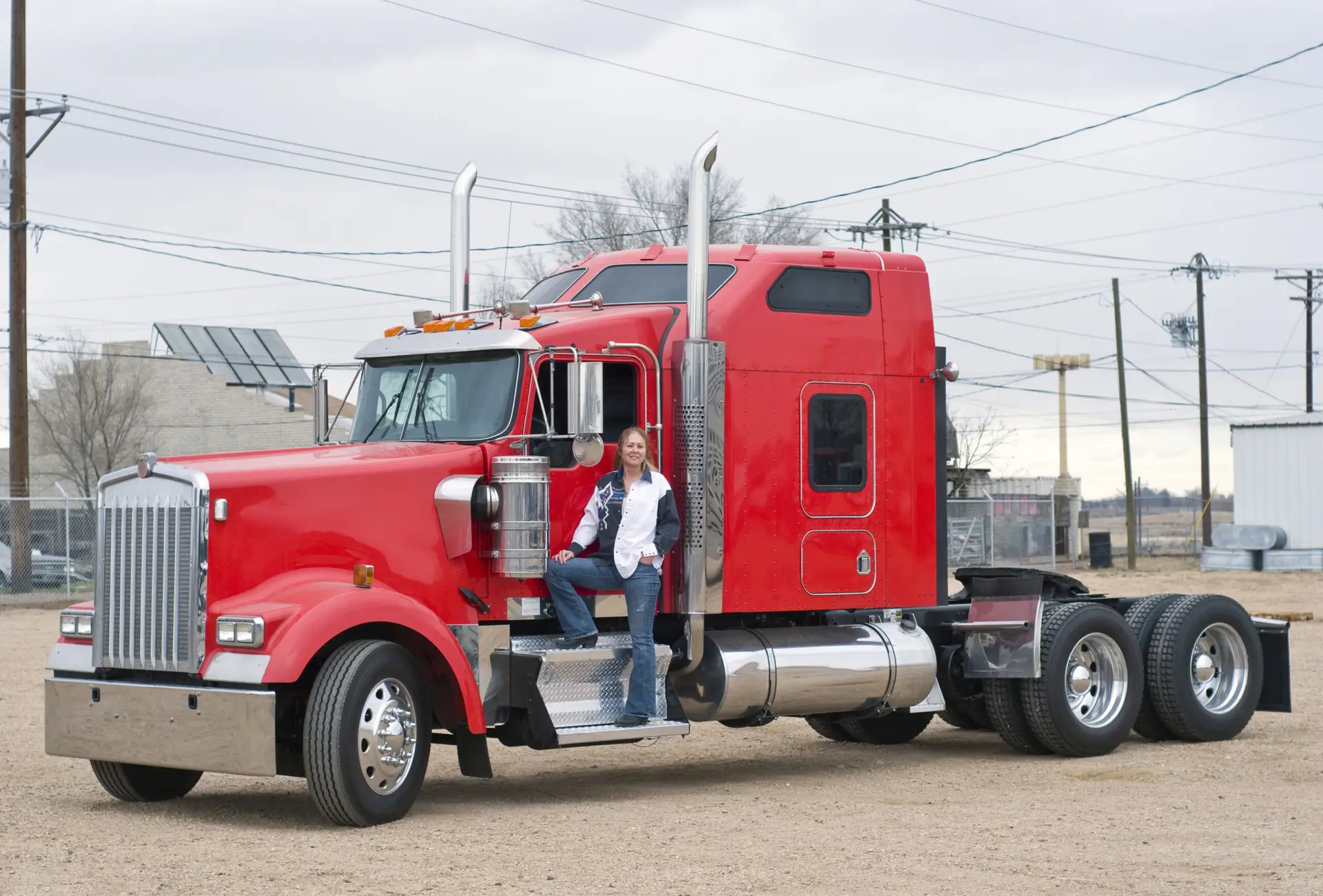 a woman driver standing on the step side of a bobtail 18 wheeler