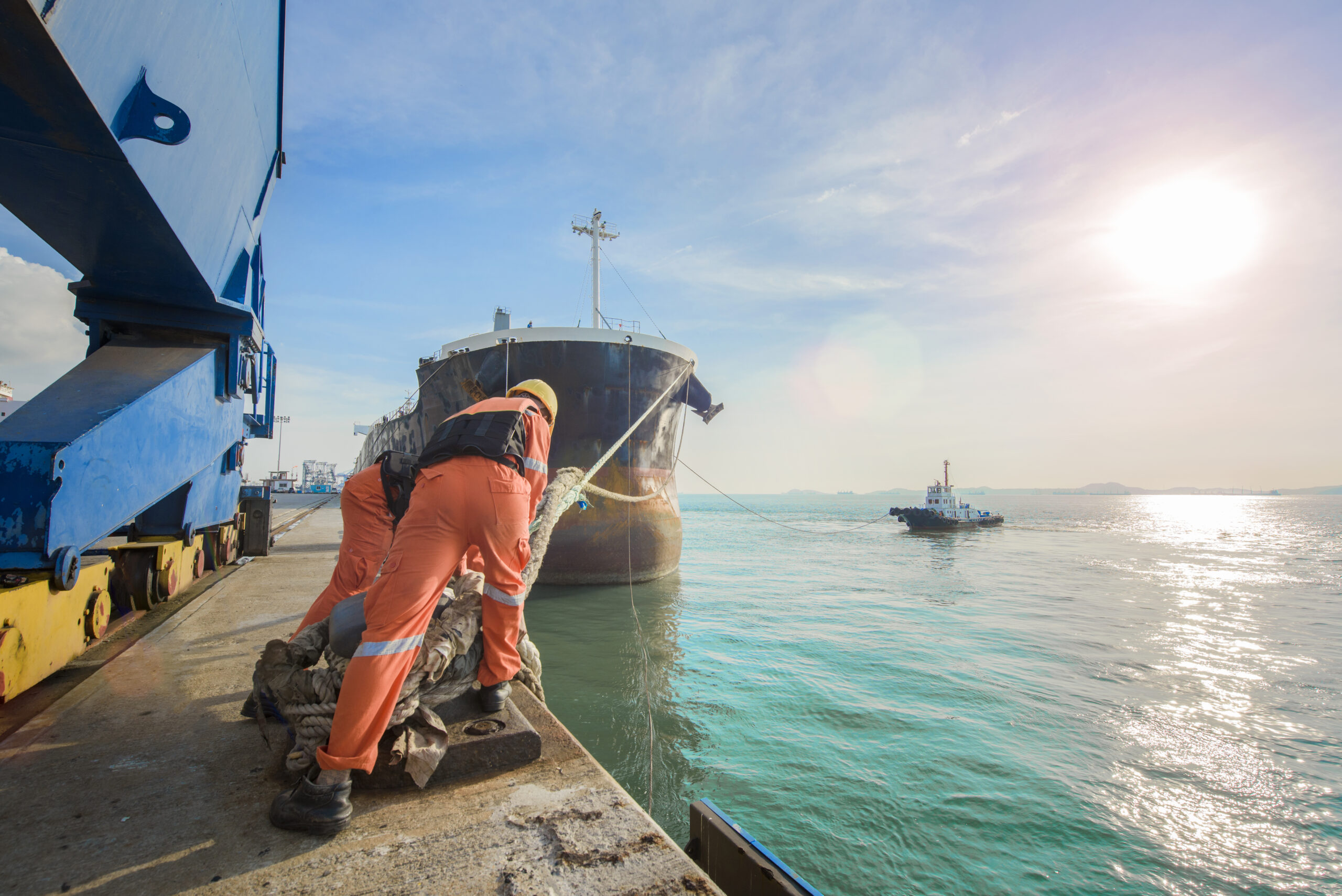 a pair of maritime workers mooring a ship to a dock