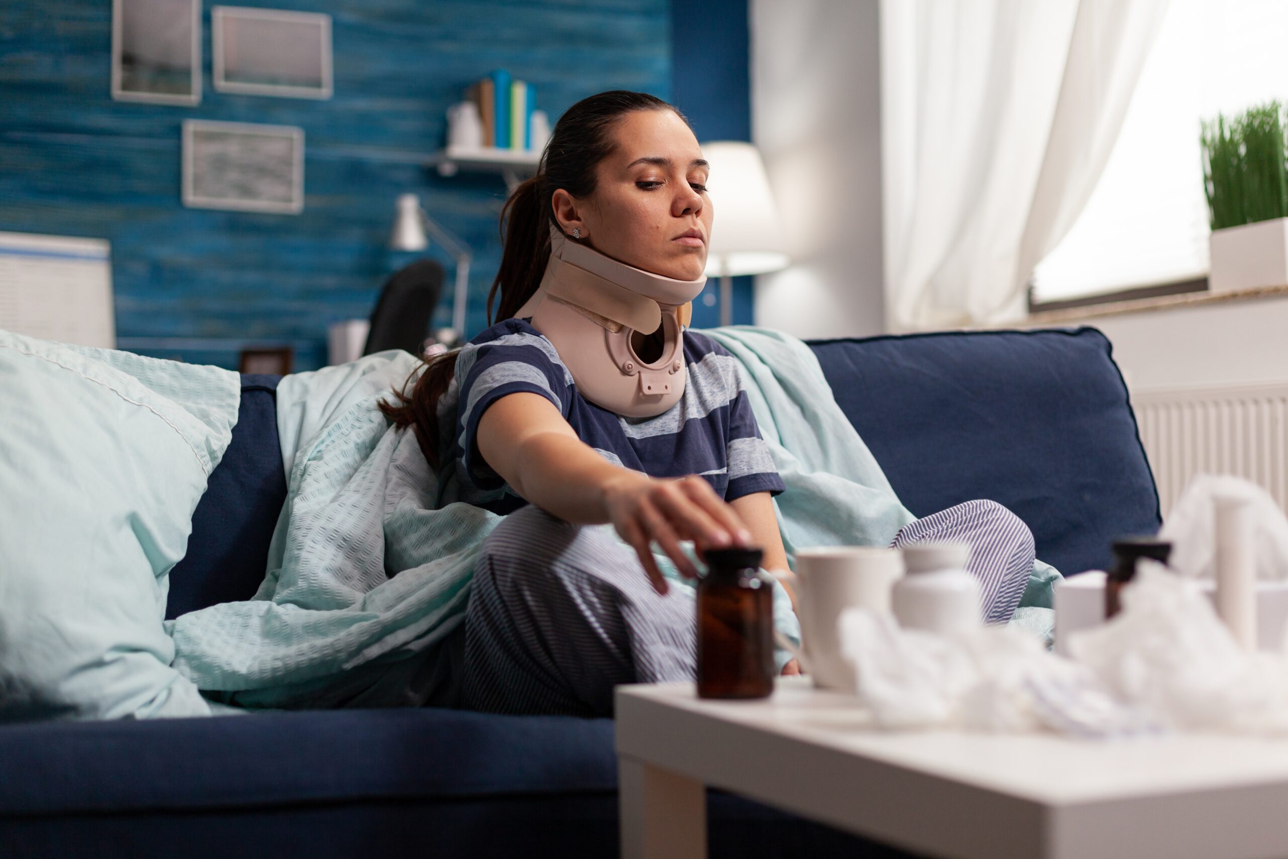 a woman sitting on her couch wearing a neck brace because of a whiplash injury