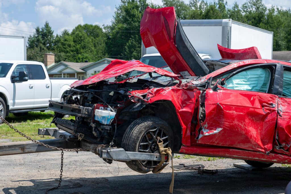 a wrecked red vehicle after a major accident being hauled away because of severe damage