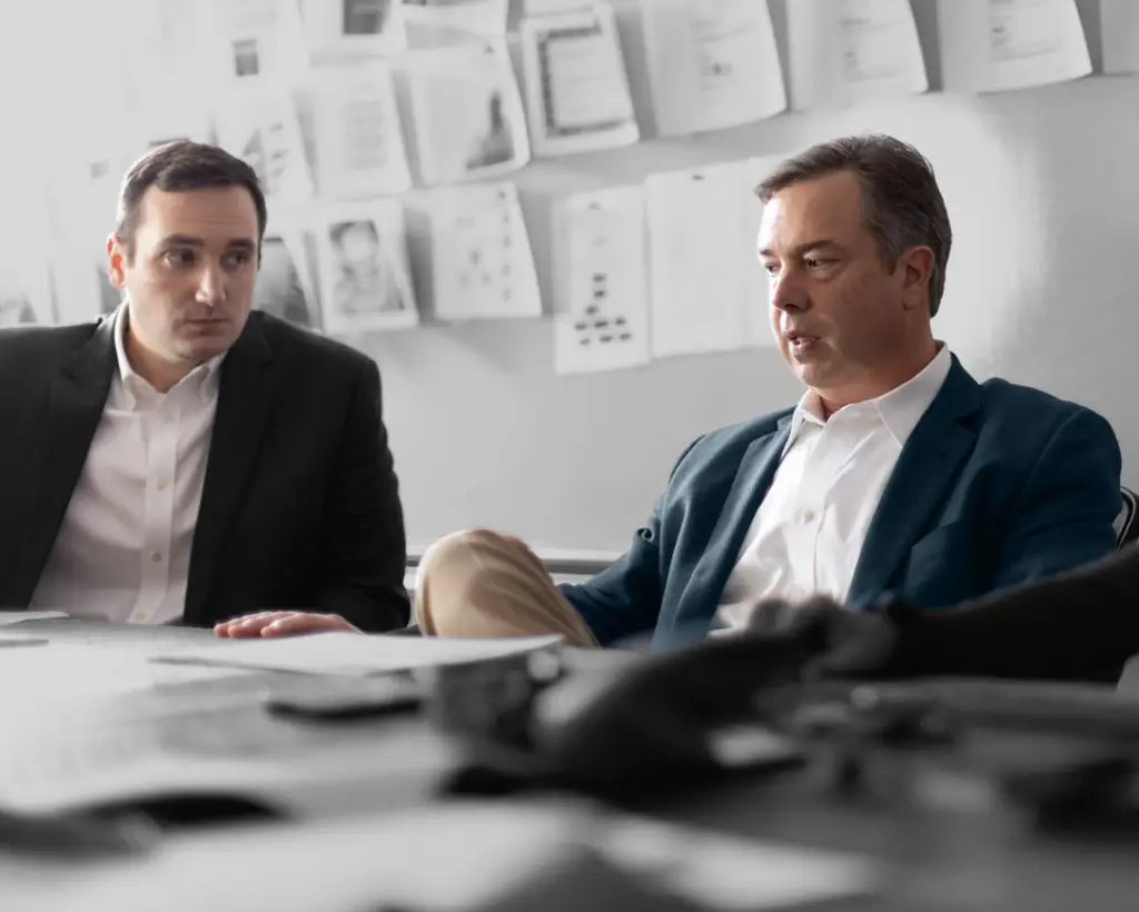 Two male attorneys in suits looking over notes and visual aids for an upcoming trial