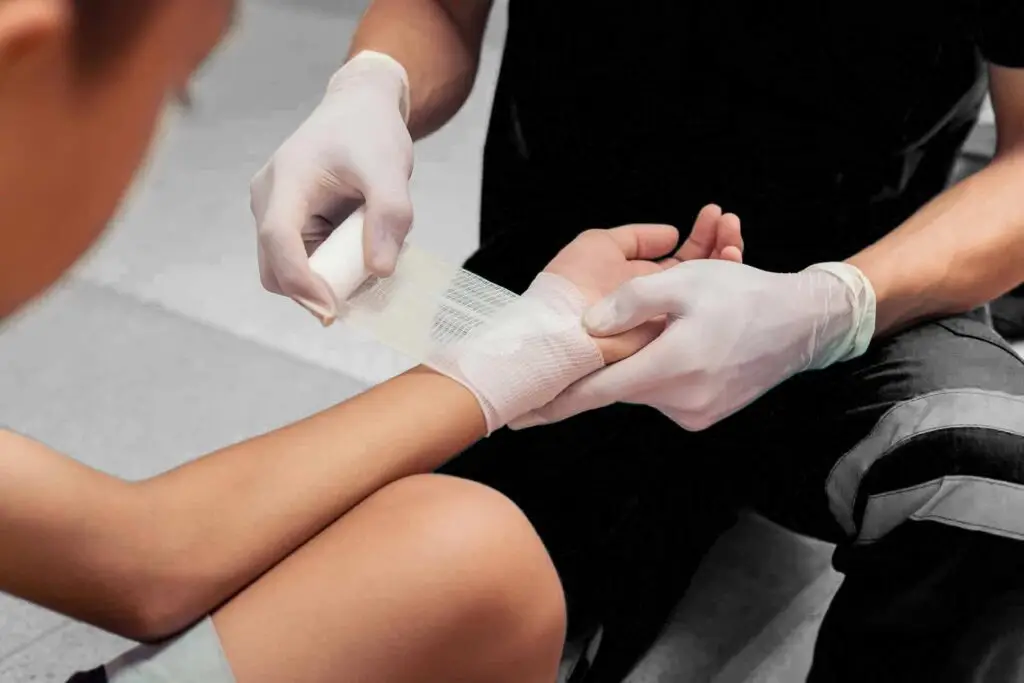 A doctor is treating a patient by wrapping bandages around their wrist.