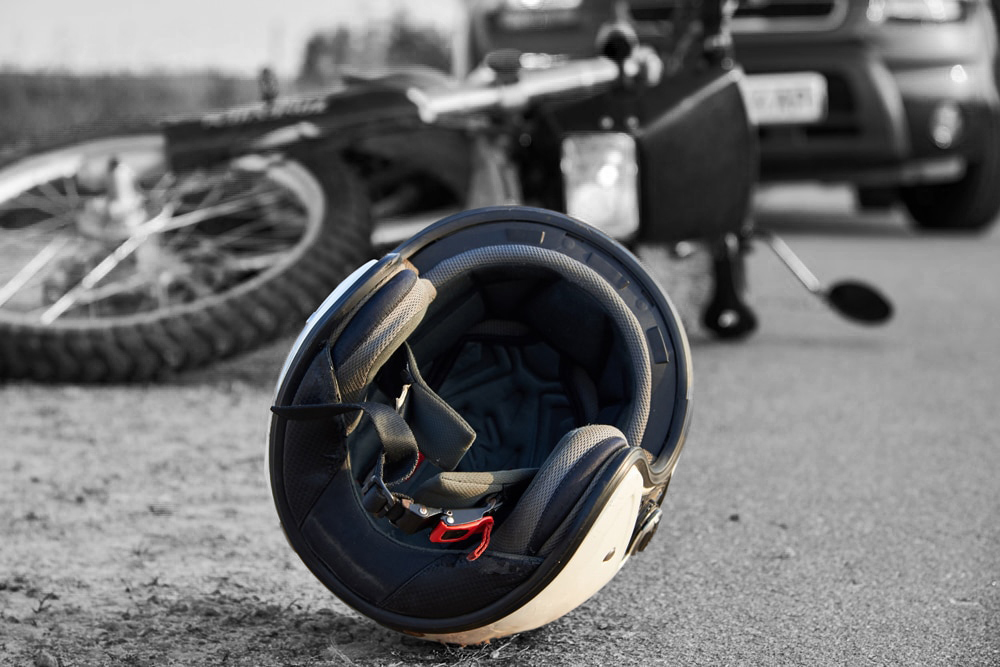 Photo of helmet and motorcycle on road, having fallen after an accident.