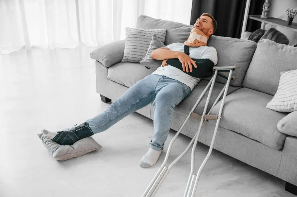 Man with crutches is at home indoors.