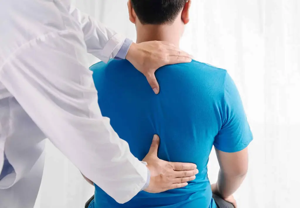 Doctor physiotherapist doing healing treatment on man's back.