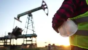 Oil,Production.,A,Worker,Holding,A,Protective,Hard,Hat,At